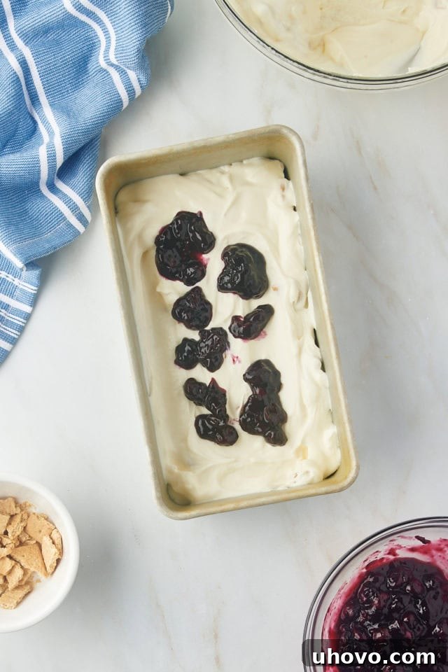 Dollops of blueberry compote carefully placed on top of the ice cream layer in the metal loaf pan.