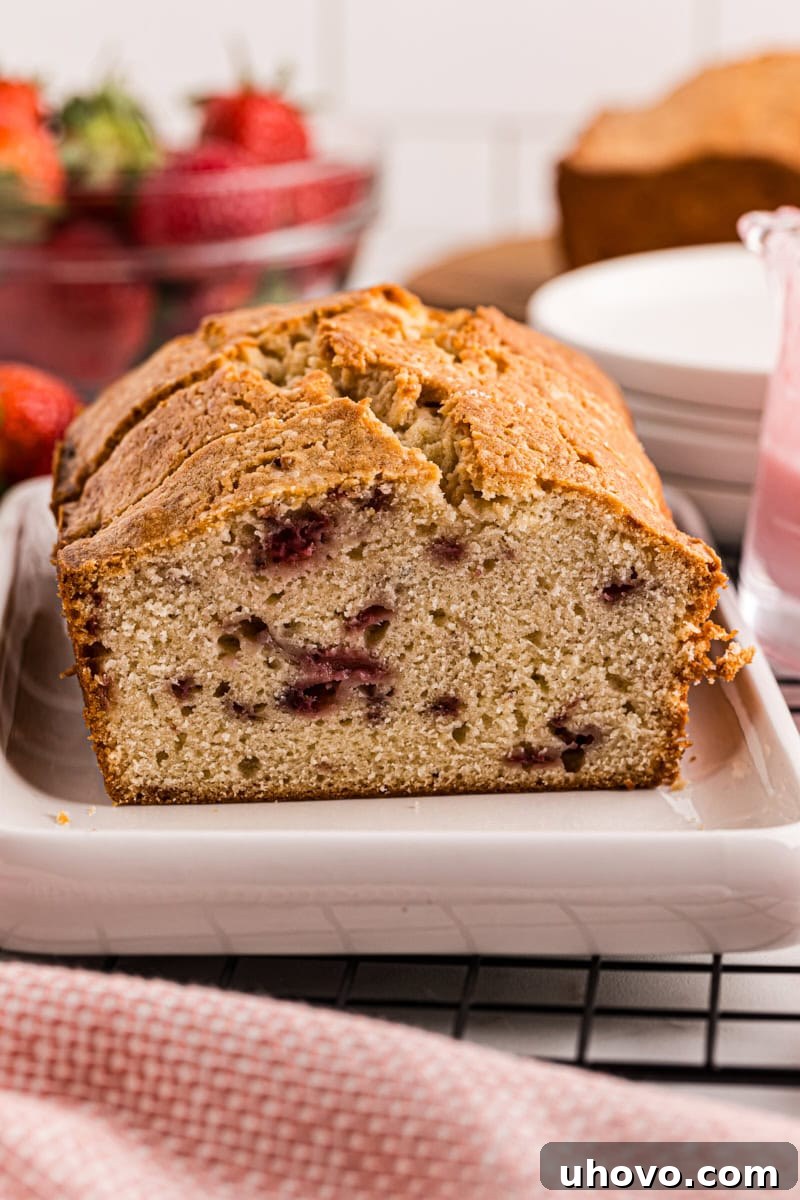 A perfectly sliced strawberry pound cake elegantly arranged on a white serving tray, showcasing its moist texture and vibrant strawberry pieces.