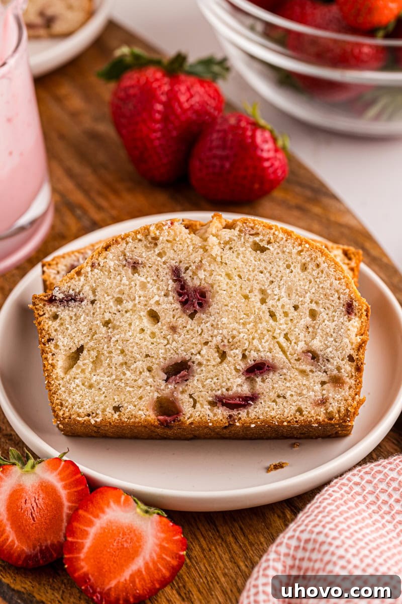 A single, perfectly cut slice of strawberry pound cake, adorned with a delicate strawberry glaze, presented on a simple white plate, ready to be savored.