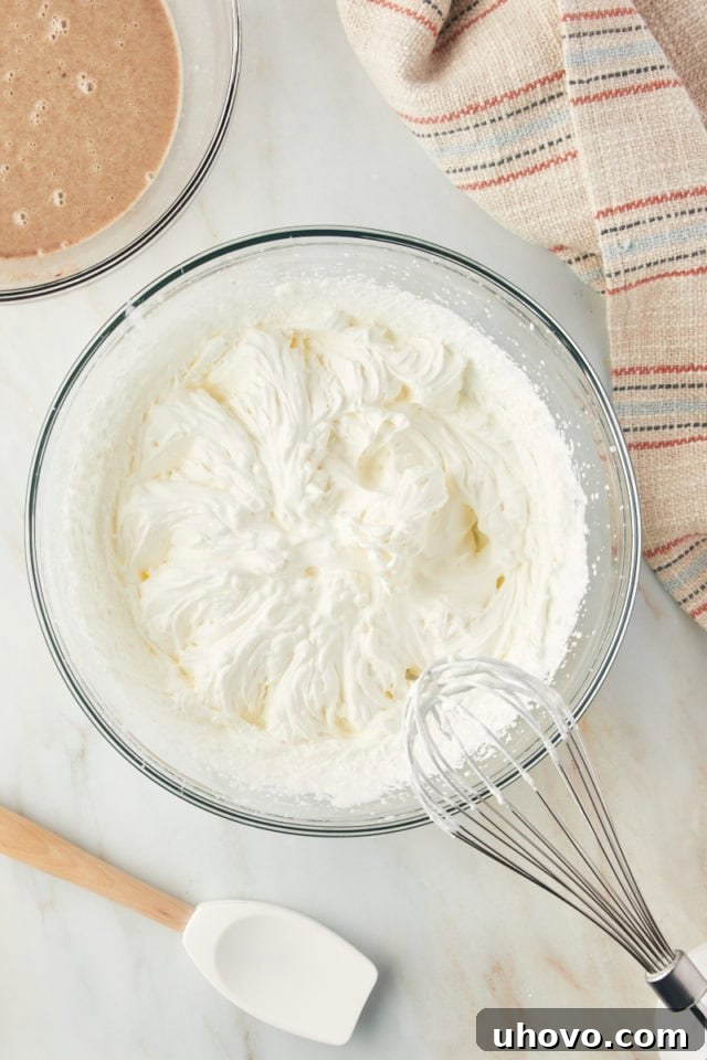 Overhead view of a bowl filled with perfectly whipped heavy cream, forming stiff peaks