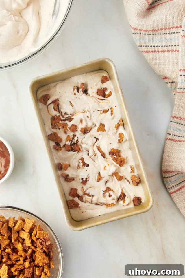 Overhead view of churro ice cream mixture in a loaf pan with graham cracker bits swirled in