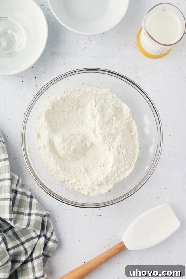Overhead view of dry ingredients—flour, sugar, baking powder, and salt—mixed together in a glass bowl, perfectly prepared for the tender cobbler topping.