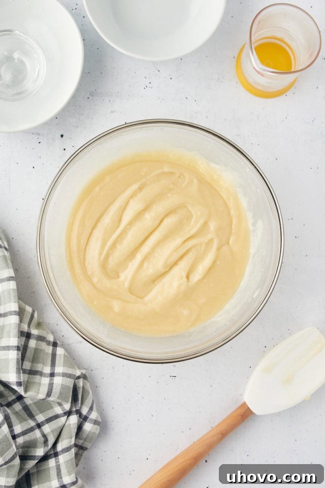 Close-up overhead view of the mixed cobbler topping batter in a glass mixing bowl, showing a smooth and well-combined texture, ready for assembly.