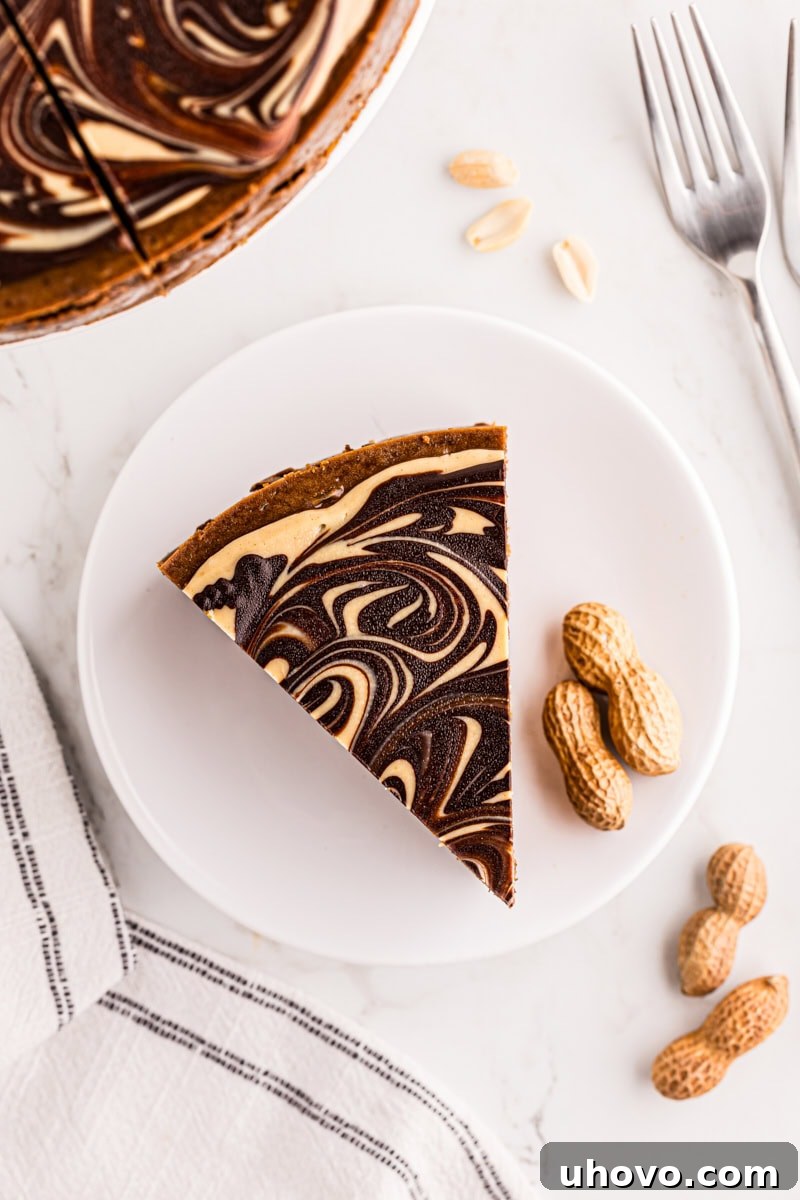 An overhead shot of a single slice of chocolate peanut butter cheesecake on a white plate, highlighting its luscious layers.