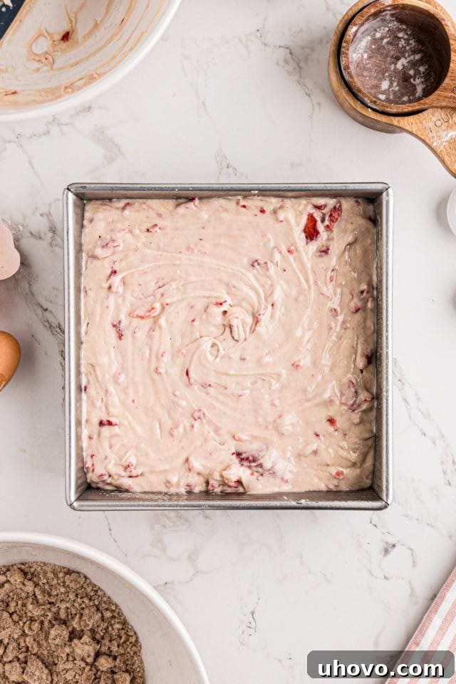 overhead view of strawberry coffee cake batter spread in a rectangular baking pan
