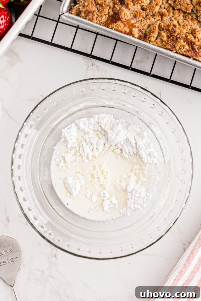 overhead view of confectioners' sugar, milk, and vanilla in a glass mixing bowl