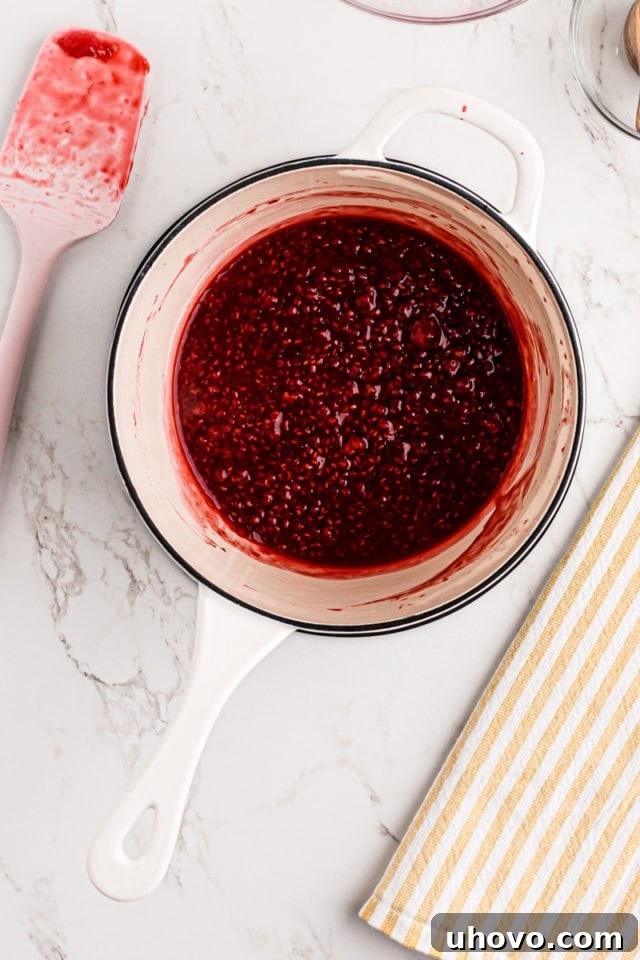 Overhead view of freshly made raspberry filling, thickened and glistening, in a saucepan.