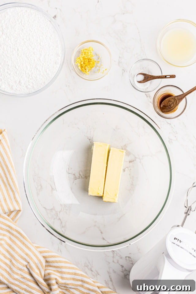 Overhead view of softened unsalted butter being beaten until creamy in a glass mixing bowl.