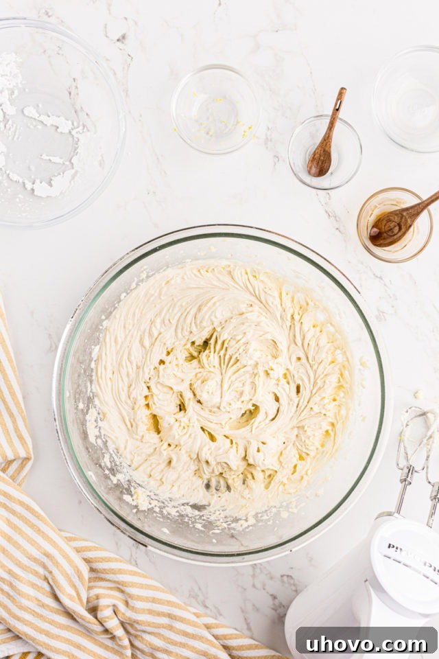 Overhead view of finished lemon frosting in a glass mixing bowl, light and fluffy.