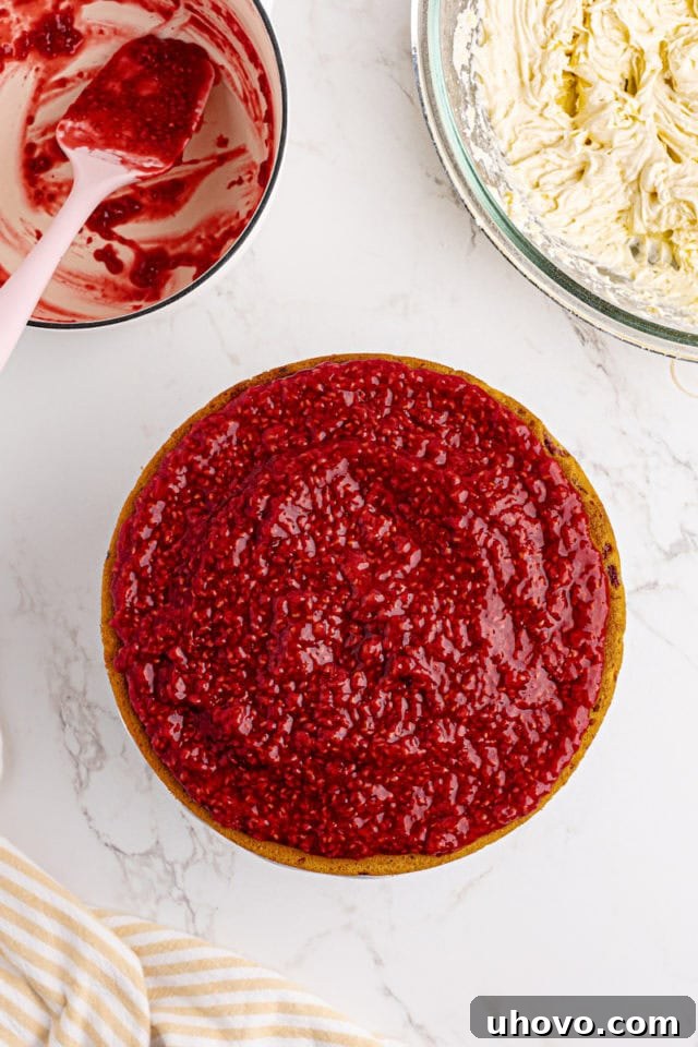 Overhead view of a lemon raspberry cake layer topped with a generous spread of homemade raspberry filling.