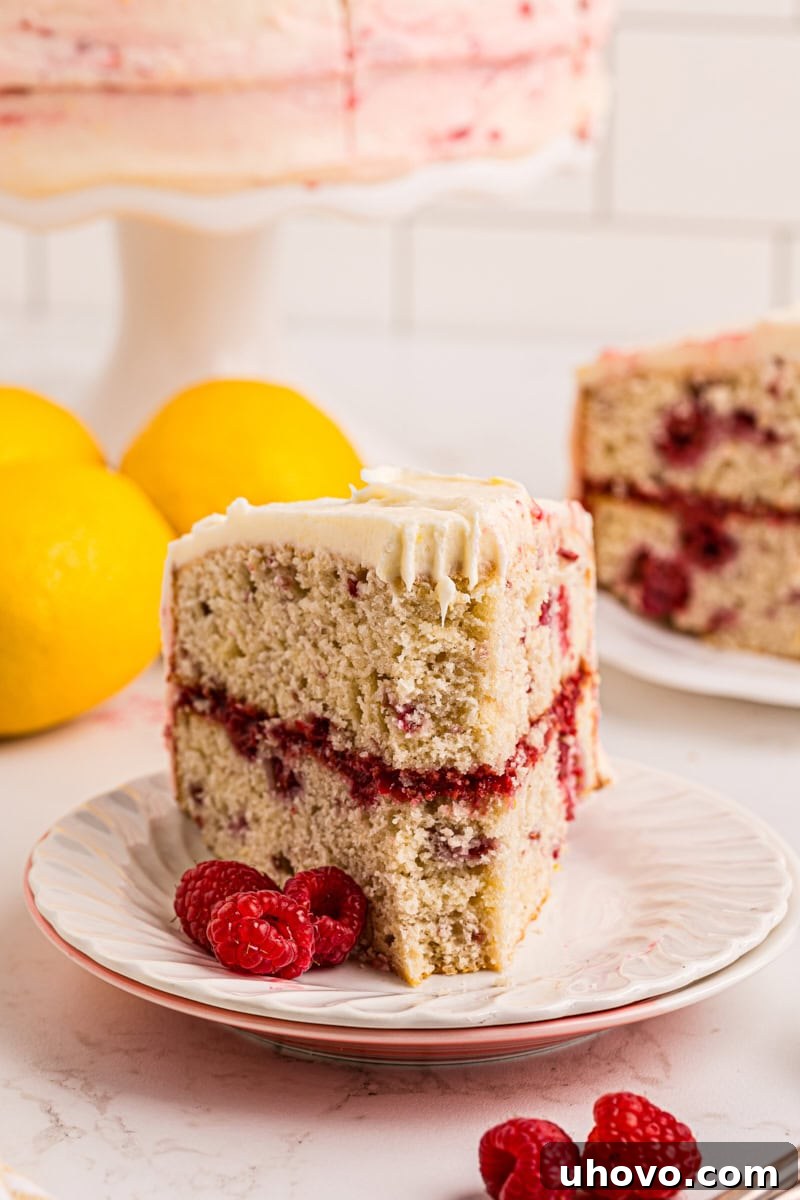 A slice of lemon raspberry cake with a bite taken out, showing the moist cake, vibrant filling, and fluffy frosting.