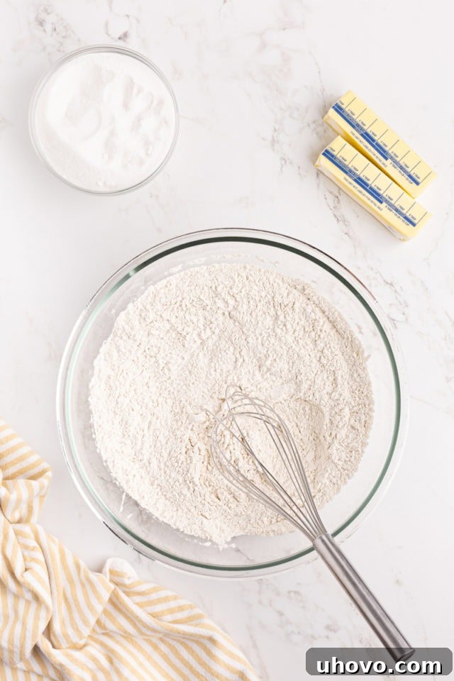 Overhead view of combined flour, baking powder, and salt in a glass mixing bowl, ready for cake batter.