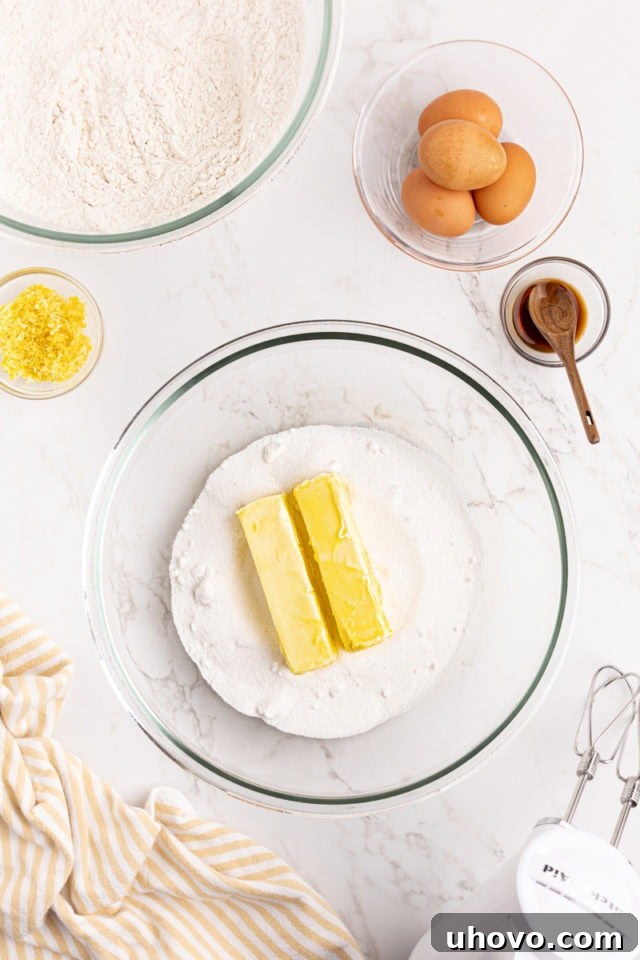 Overhead view of softened unsalted butter and granulated sugar in a glass mixing bowl, creamed together.