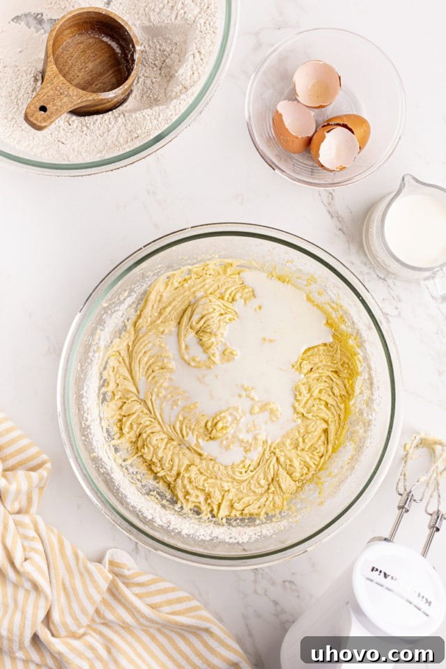 Overhead view of milk being poured into the lemon raspberry cake batter during mixing.