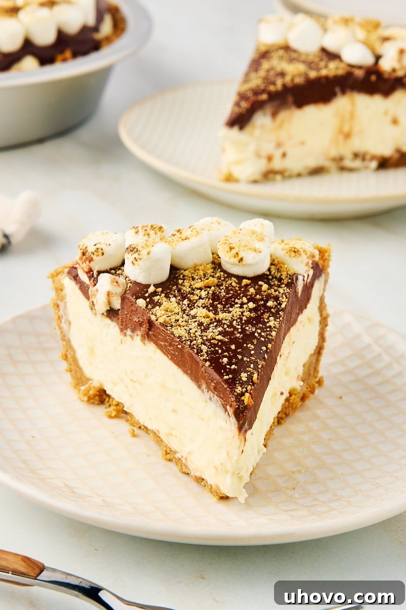a slice of s'mores pie on a white and beige plate with more pie in the background