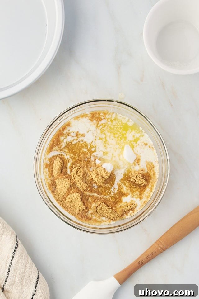 overhead view of graham cracker crumbs, melted butter, and sugar in a glass mixing bowl