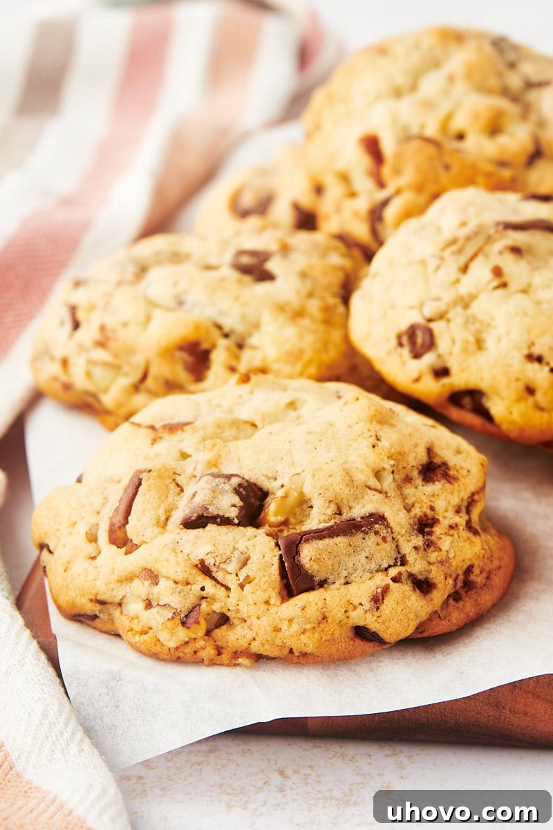 Thick chocolate chip cookies cooling on parchment paper, showcasing their impressive height and golden-brown edges.