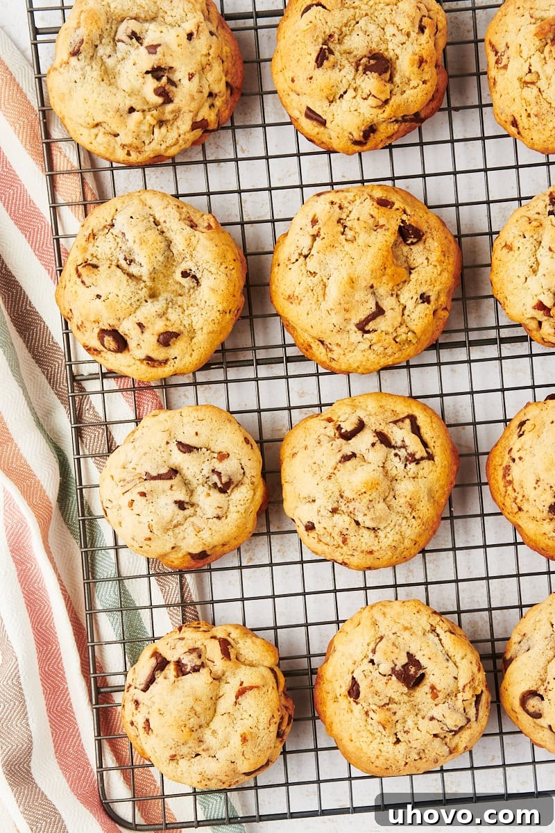 Thick chocolate chip cookies cooling on a wire rack, showcasing their texture and size.
