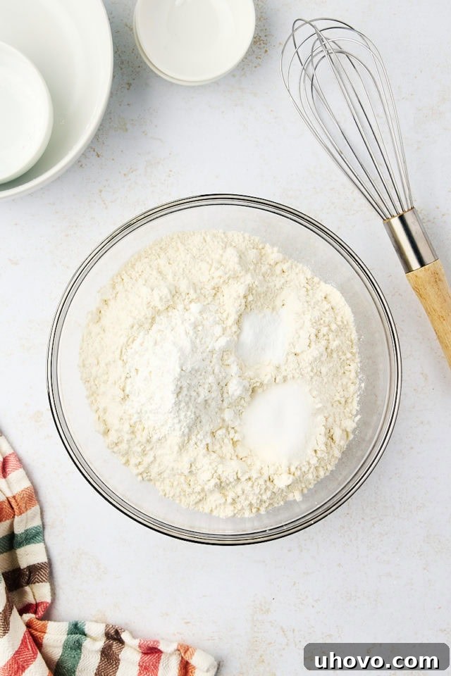 Overhead view of flour, cornstarch, baking soda, and salt mixed in a glass bowl.