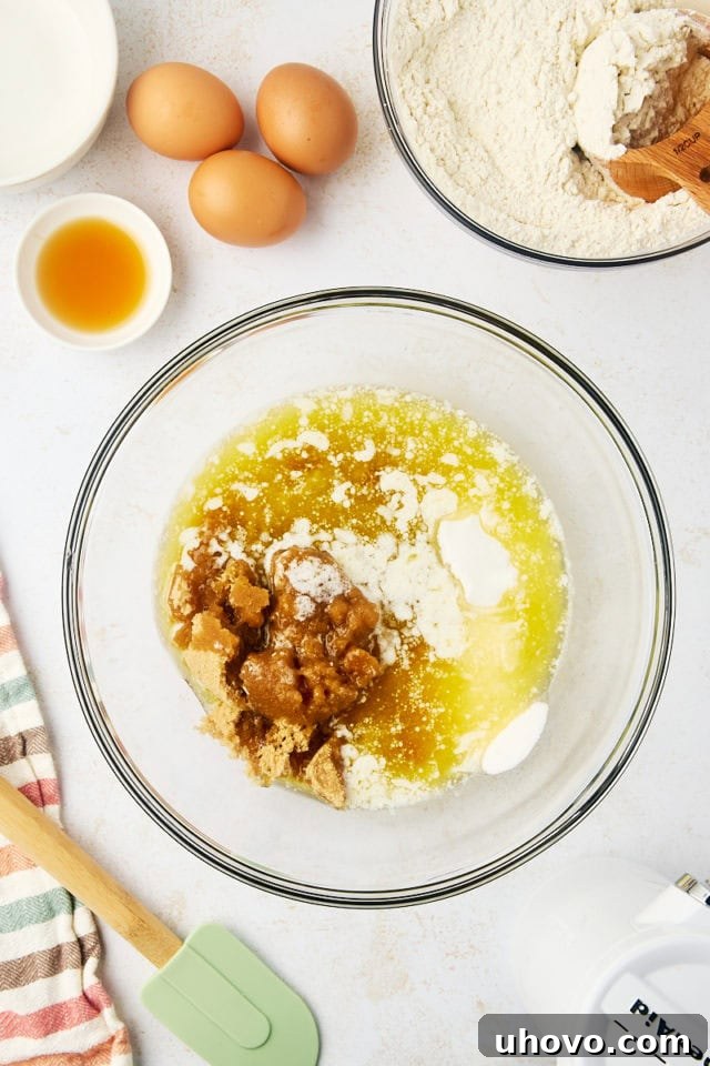 Overhead view of melted butter, brown sugar, and granulated sugar combined in a glass mixing bowl.