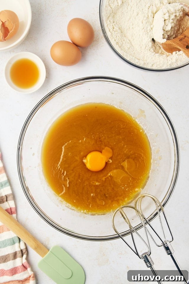 Overhead view of an egg being added to the butter and sugar mixture for cookie dough.
