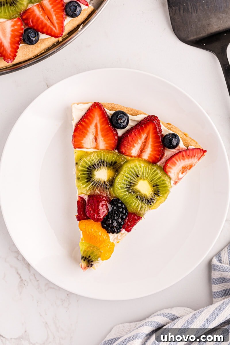 overhead view of a slice of fruit pizza on a white plate