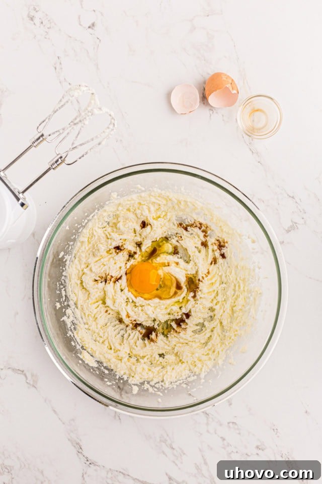 overhead view of egg and vanilla added to creamed butter and sugar in a glass mixing bowl
