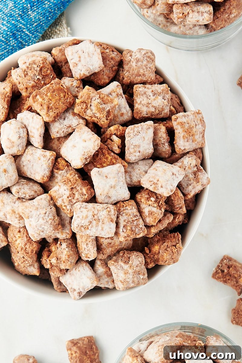 overhead view of muddy buddies in a white bowl, a perfectly coated, sweet, and crunchy snack