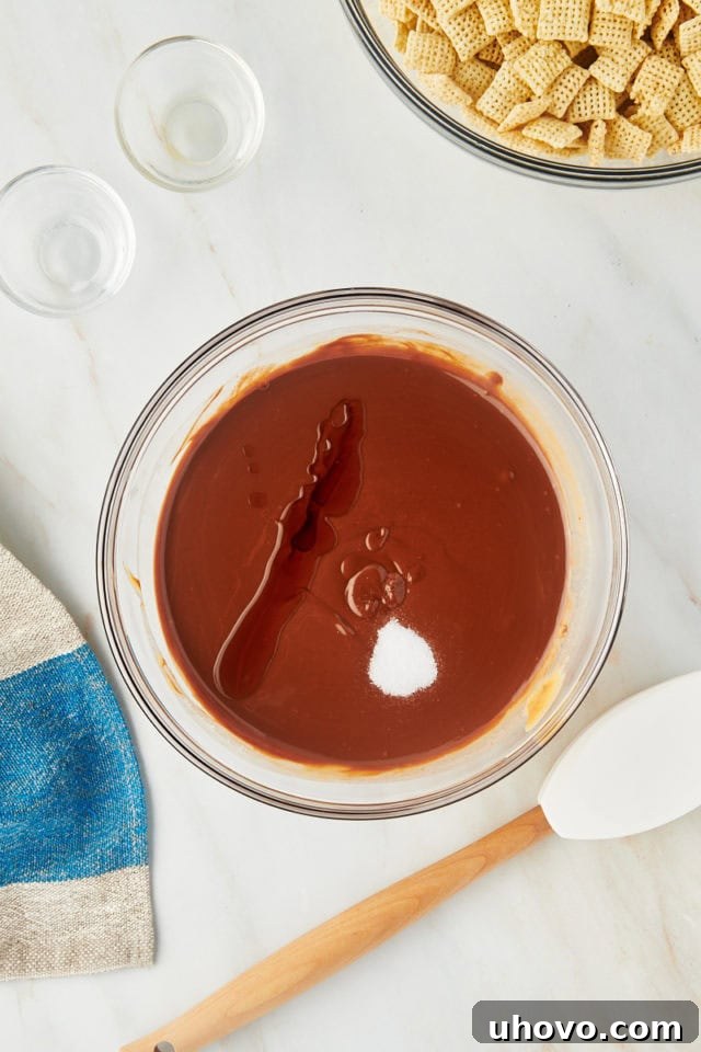 overhead view of vanilla extract and salt being added to the smooth, melted chocolate, peanut butter, and butter mixture