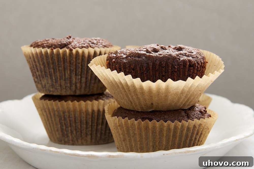A closer look at Mocha Muffins, stacked on a white plate, revealing their moist texture and scattered chocolate chips.
