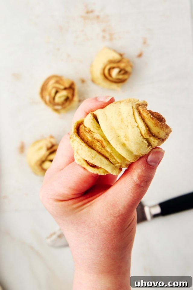 A detailed shot showing how to carefully coil a strip of cruffin dough around a finger, demonstrating the shaping technique.