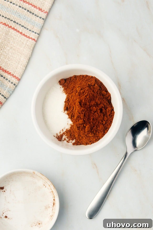 An overhead shot of granulated sugar and ground cinnamon beautifully combined in a small white bowl, ready for the cruffin filling.