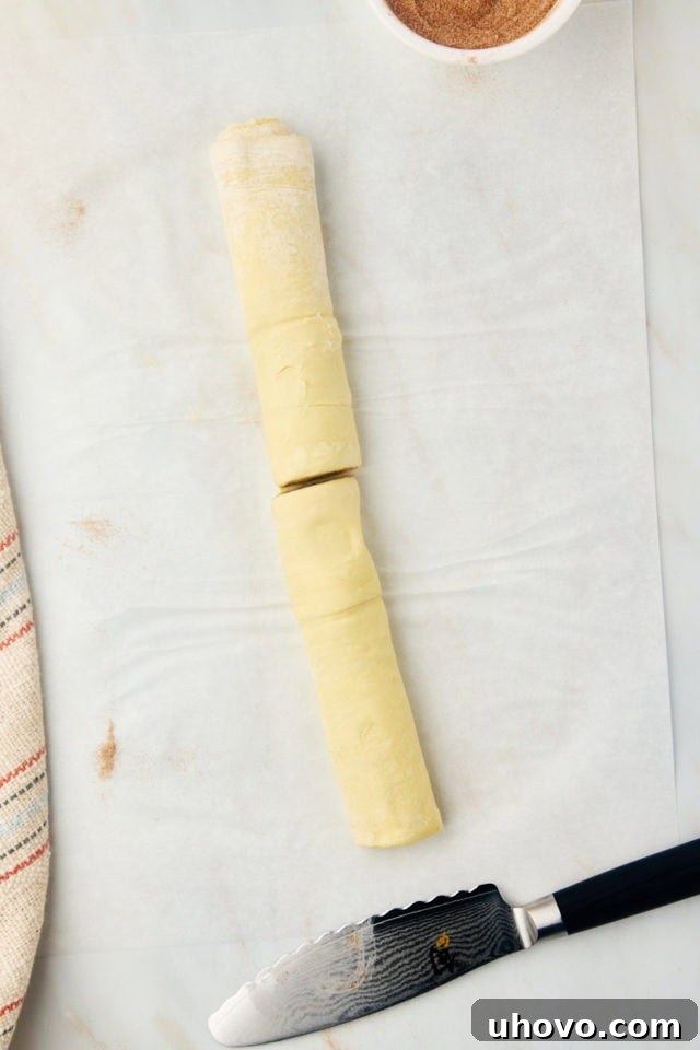 A crisp, overhead image of the rolled cruffin dough log, now precisely cut in half, showing its two equal portions.
