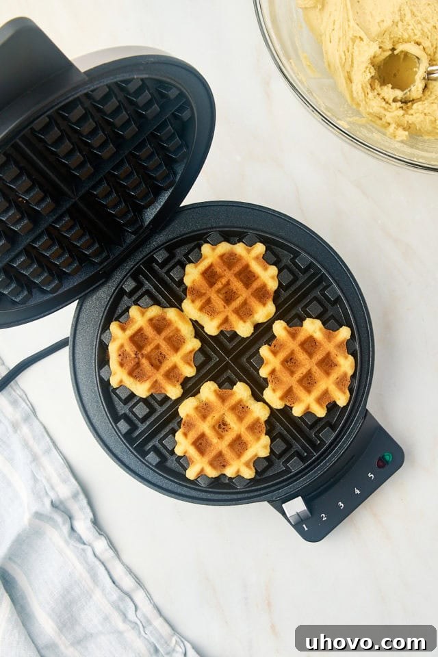 Overhead view of freshly made waffle cookies inside an open waffle maker, golden brown and perfectly textured after cooking for a few minutes.