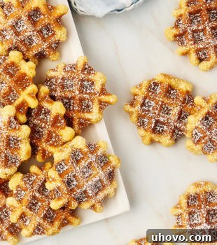 Overhead view of waffle cookies on a white plate and scattered on a countertop