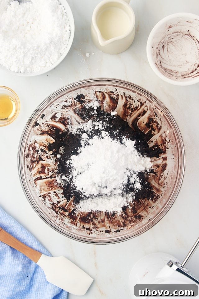 overhead view of confectioners' sugar added to frosting mixture