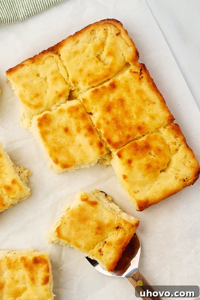 Overhead view of partially pulled apart butter swim biscuits on parchment paper, showing their soft, fluffy texture.