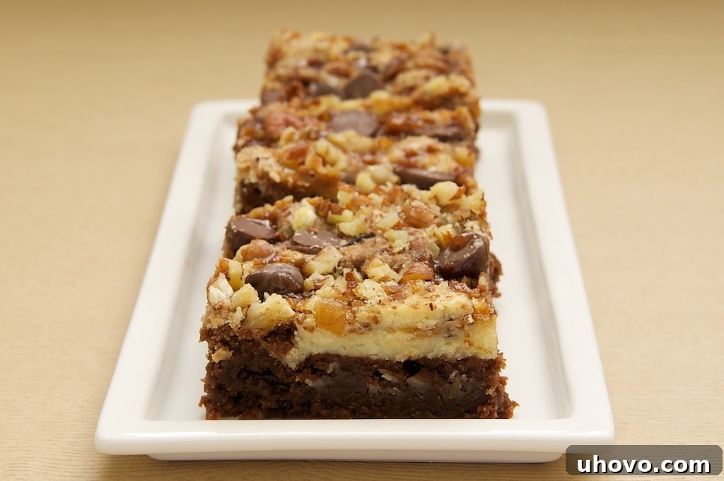Closeup of cream cheese brownies with toffee and pecans on narrow rectangular platter