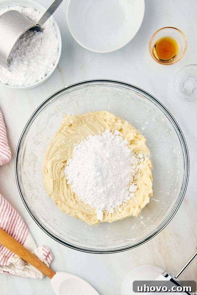 Overhead view of confectioners' sugar being gradually added to the brown sugar cream cheese frosting mixture.