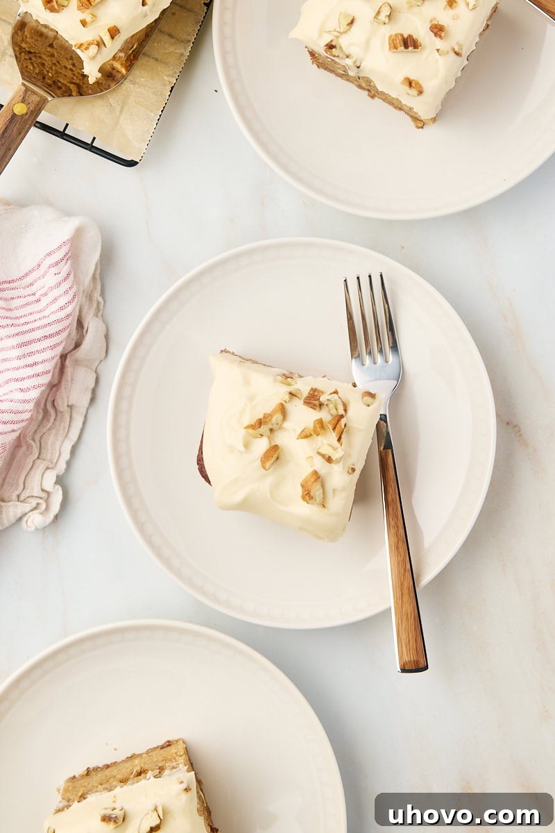 Overhead view of multiple slices of applesauce cake on various white and beige plates, showcasing the moist texture and generous frosting.