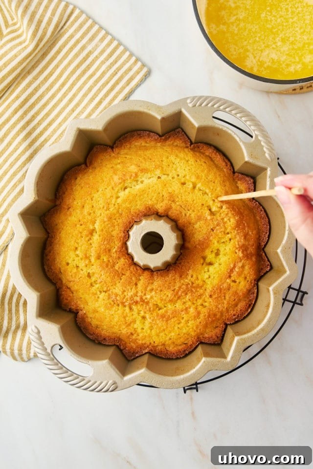 overhead view of holes being poked into warm Kentucky butter cake in a Bundt pan