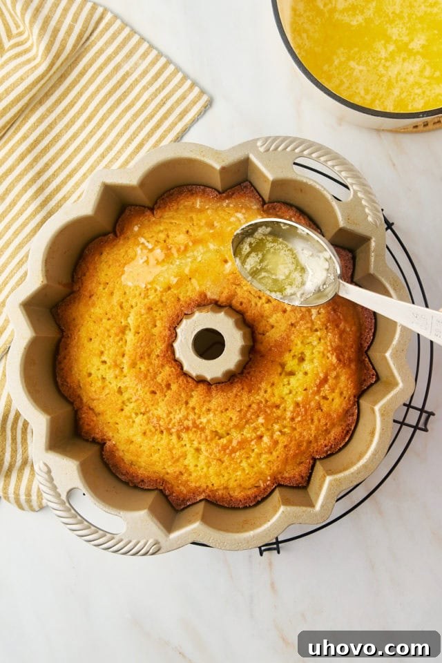 overhead view of butter glaze being spooned over warm Kentucky butter cake in a Bundt pan