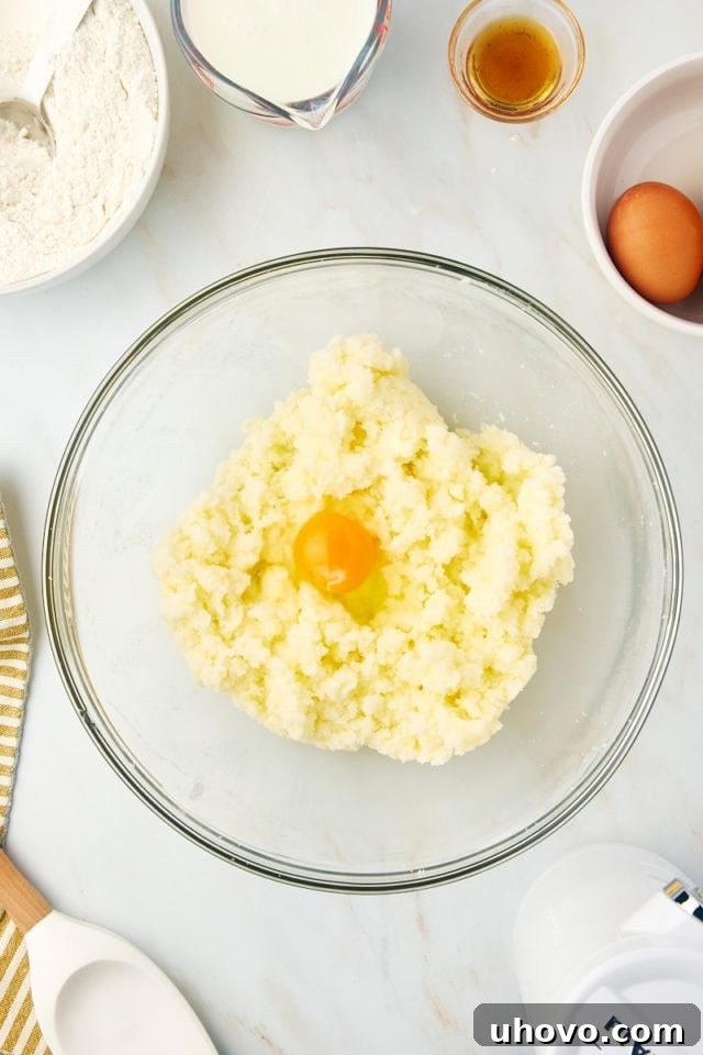overhead view of egg added to creamed butter and sugar in a glass mixing bowl