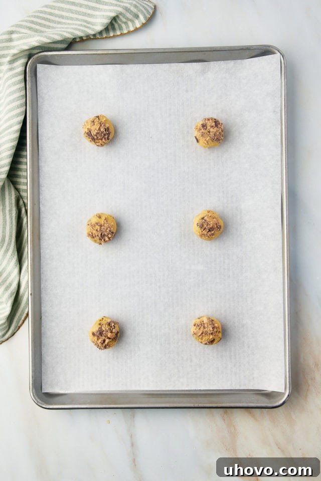 Balls of Heath bar cookie dough arranged on a parchment-lined baking sheet.