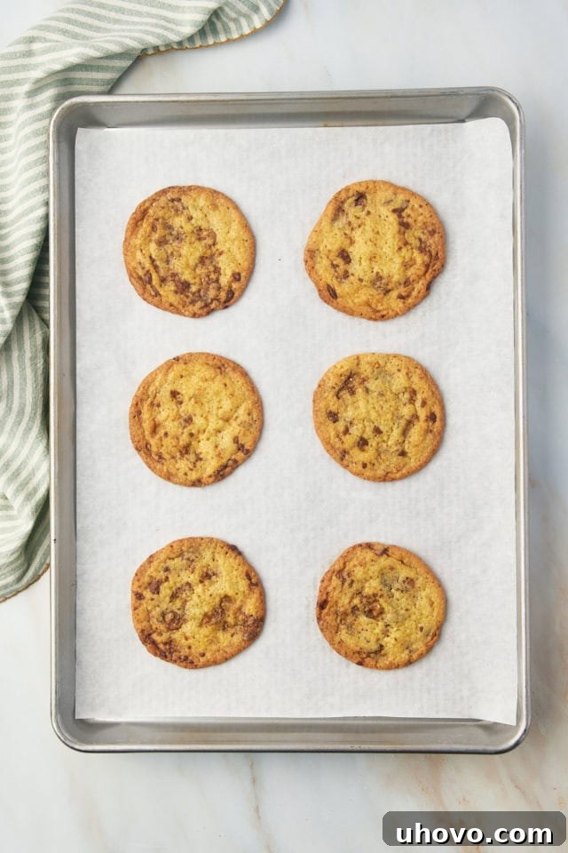 Freshly baked Heath bar cookies cooling on a baking sheet, with golden-brown edges.