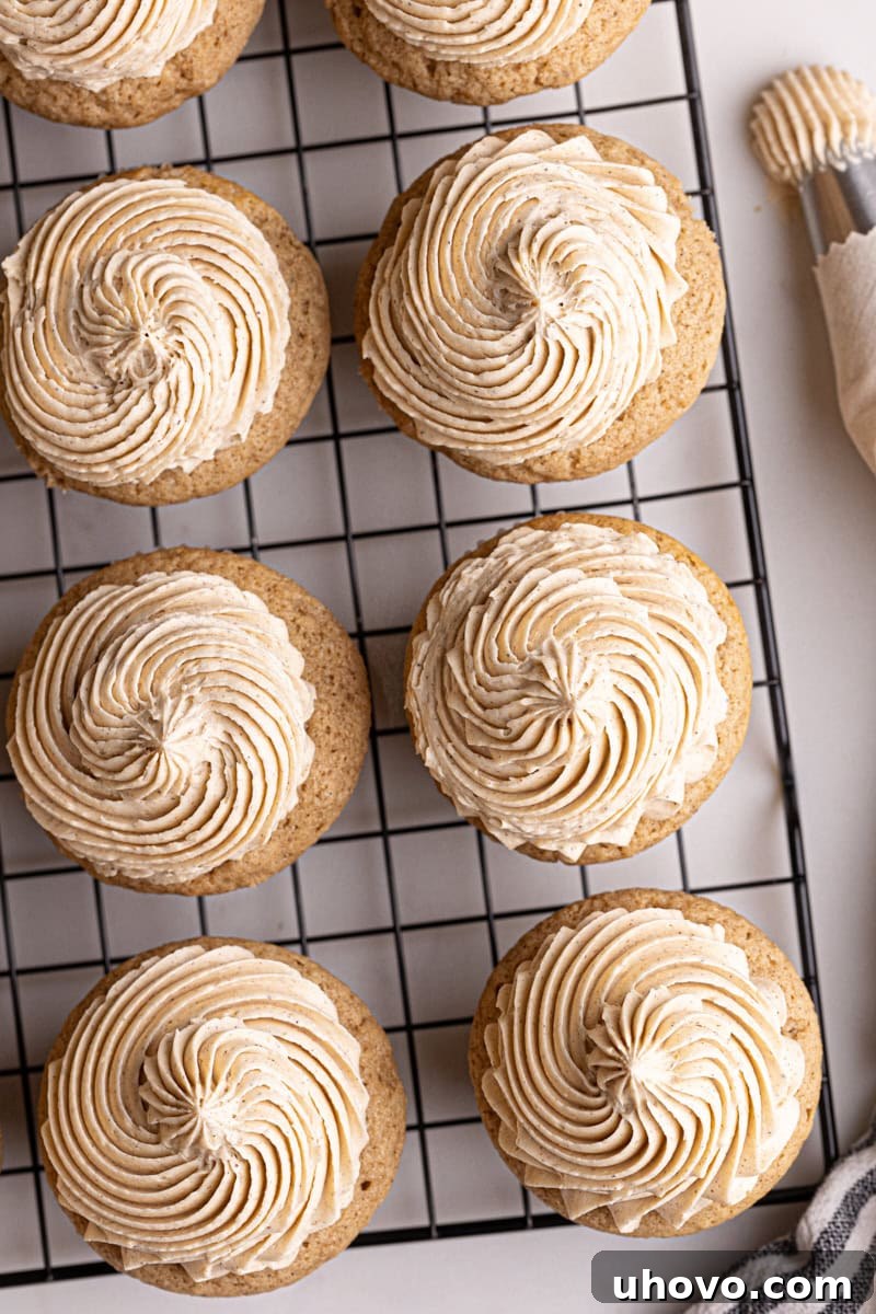 Overhead view of an array of freshly frosted chai spice cupcakes resting on a wire rack, glistening and ready.