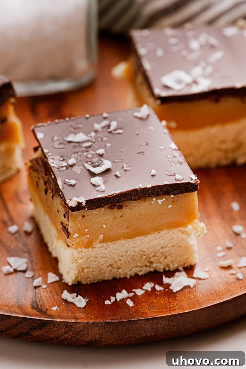 A single Millionaire Shortbread Bar, showcasing its perfect layers, resting on a wooden cutting board, ready to be enjoyed, highlighting its luxurious texture.
