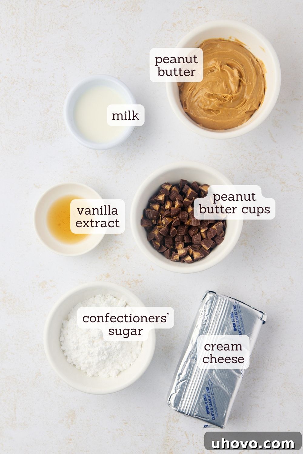 Overhead view of all the simple ingredients laid out for making the peanut butter cup dip: cream cheese, peanut butter, milk, vanilla, confectioners' sugar, and chopped peanut butter cups.