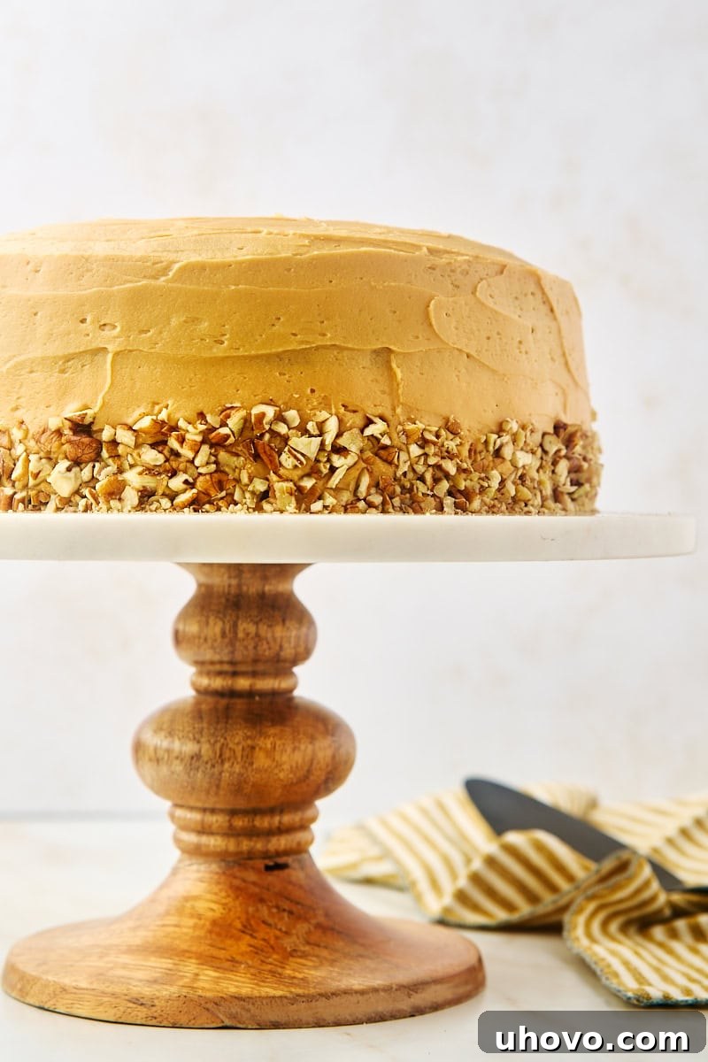 A grand dulce de leche cake prominently displayed on a elegant marble and wooden cake stand, showcasing its frosted layers and inviting texture.