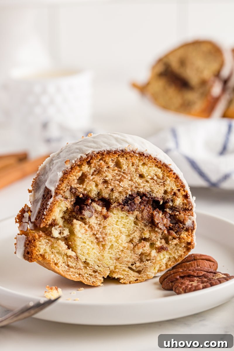 A glorious slice of glazed Cinnamon Roll Cake resting on a plate, showcasing its beautiful cinnamon and brown sugar filling.